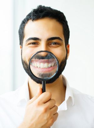 man holding a magnifying glass in front of his smile 